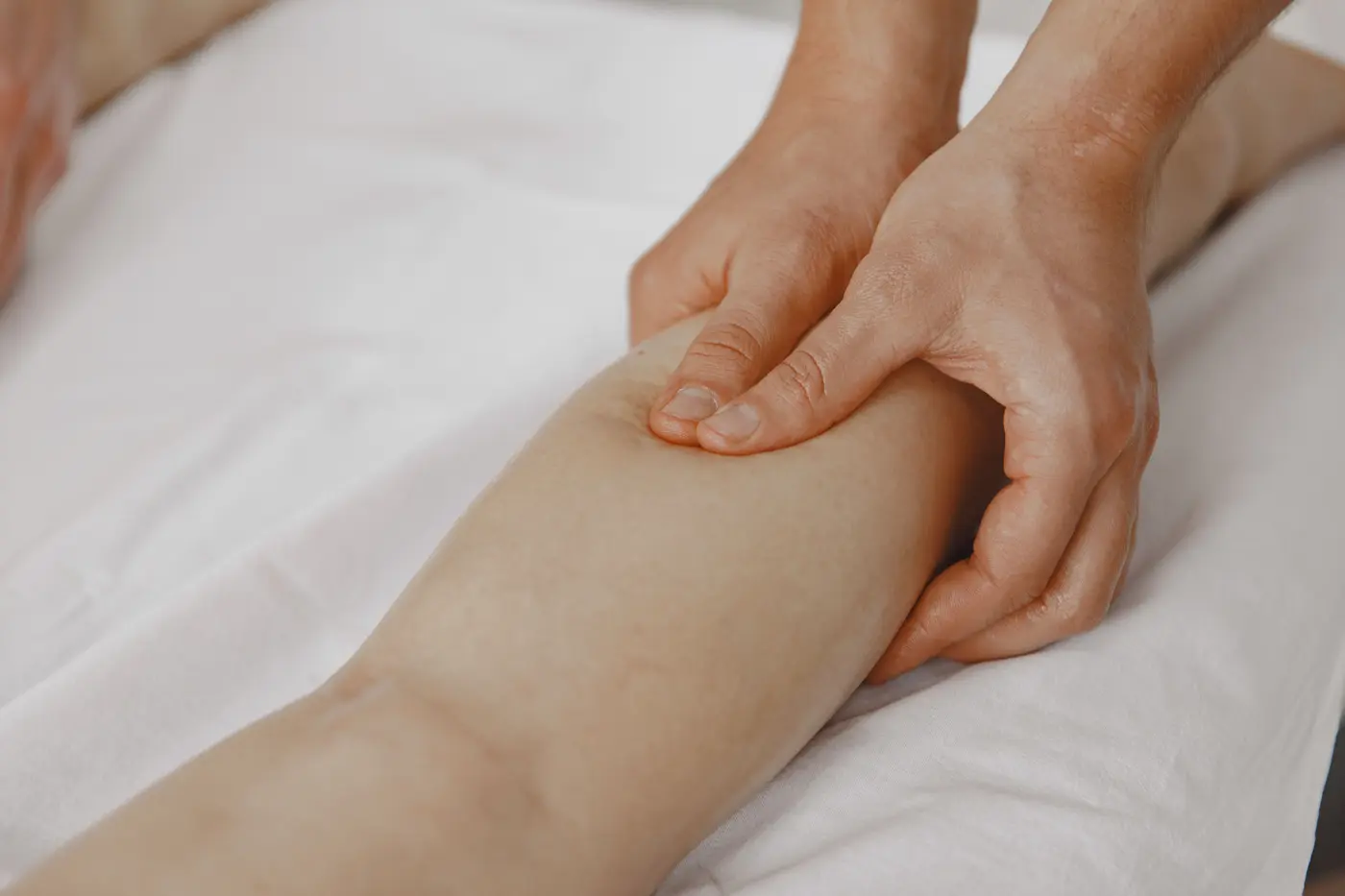 Manos de fisioterapeuta realizando drenaje manual en el brazo de una persona